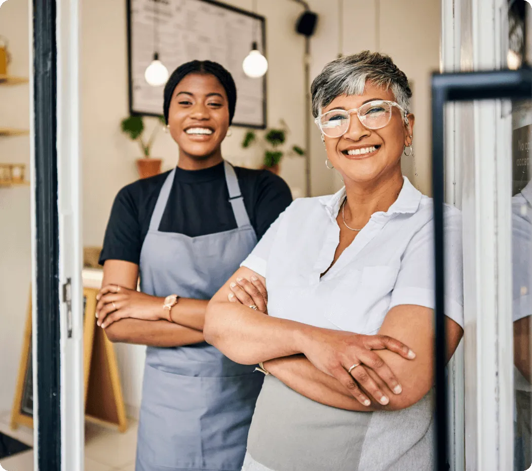 Two smiling small business owners standing at the entrance of their shop, representing effective communication for small teams with a VoIP phone system